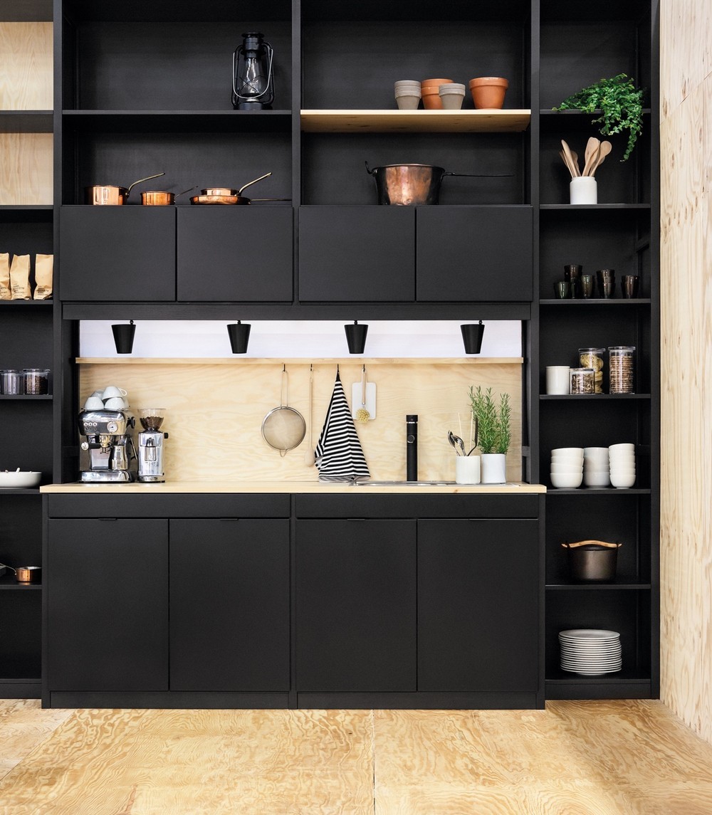 Kis fekete konyhabútor nyers faszínű padlóval