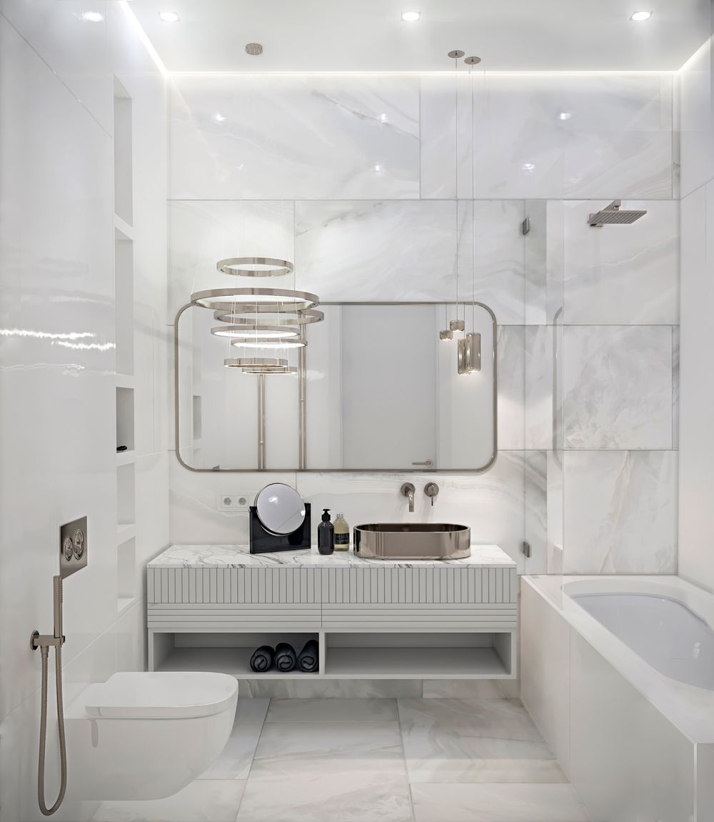 Lekeretkített sarkú tükör és kör alakú lampák finomítják a fürdőt