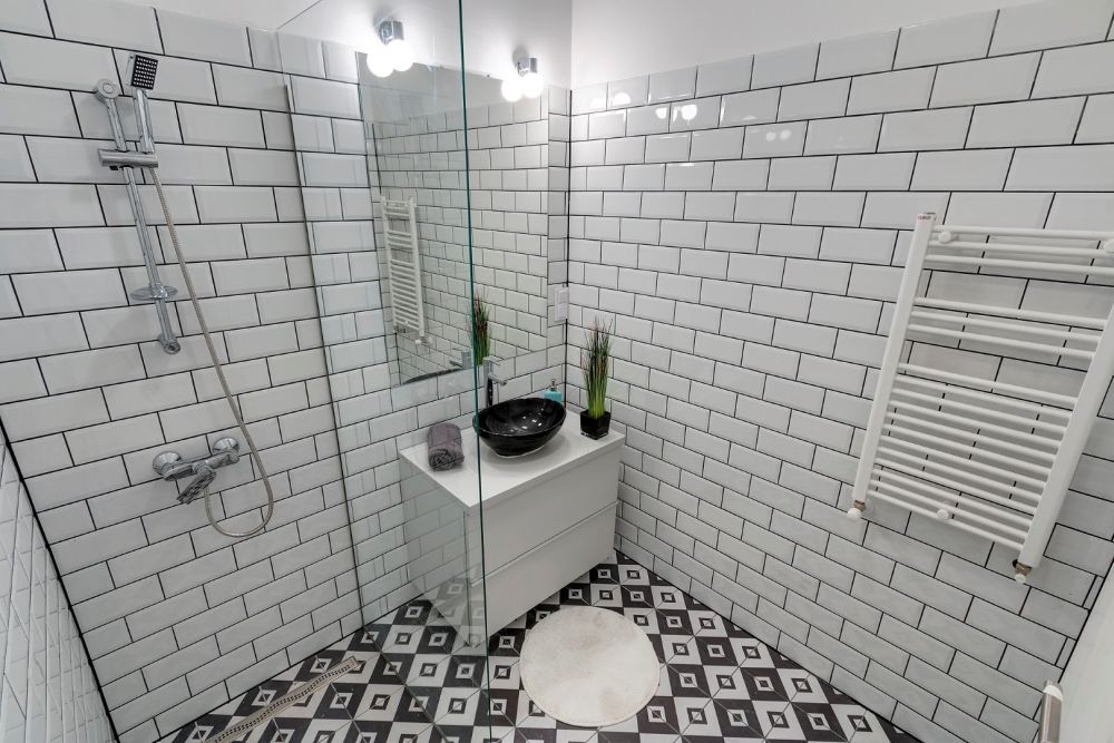 Fürdőszoba modern mintás padlólappal, fehér fényes metró csempével
