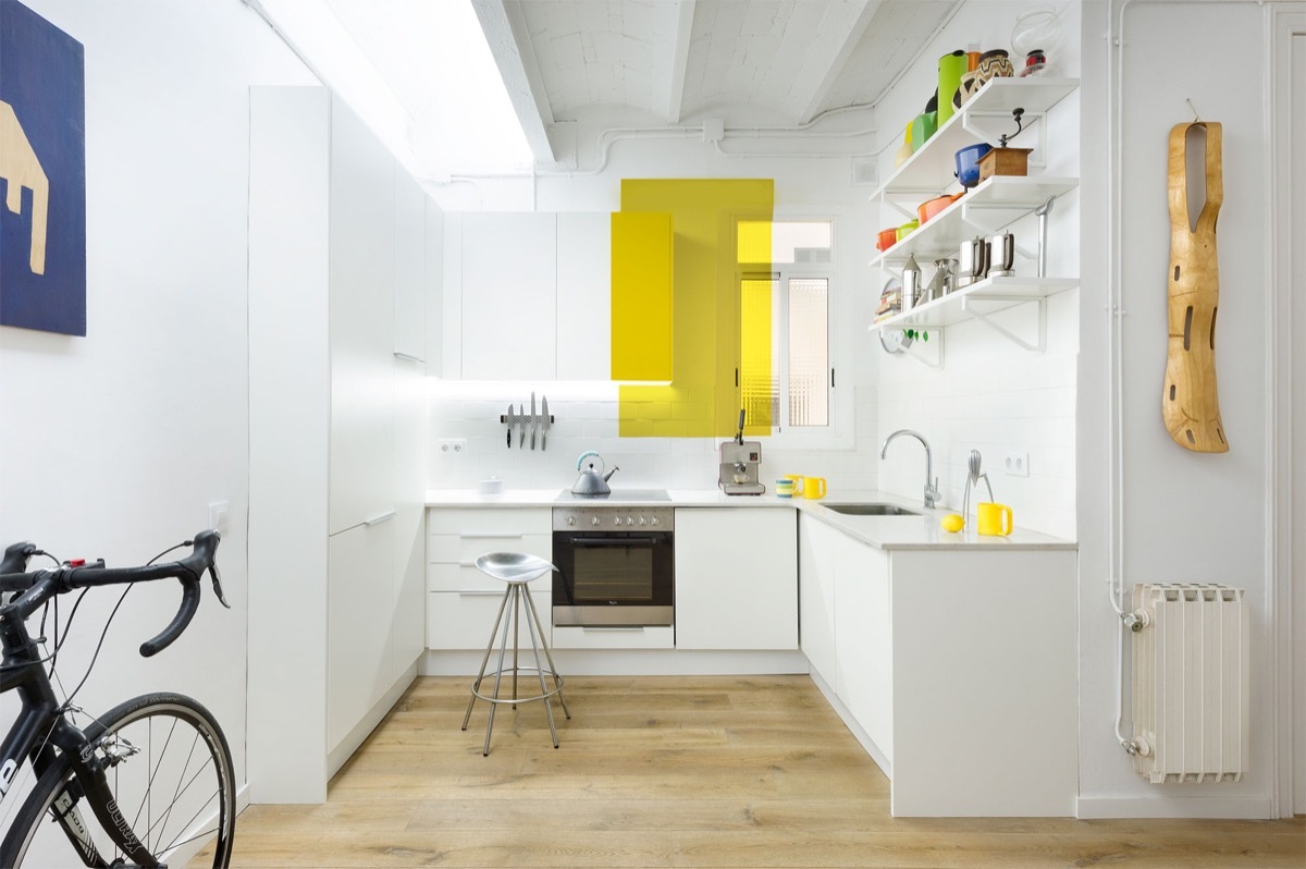 L-alakú konyha hófehérben kevés sárga dekorral, nyitott polcokkal