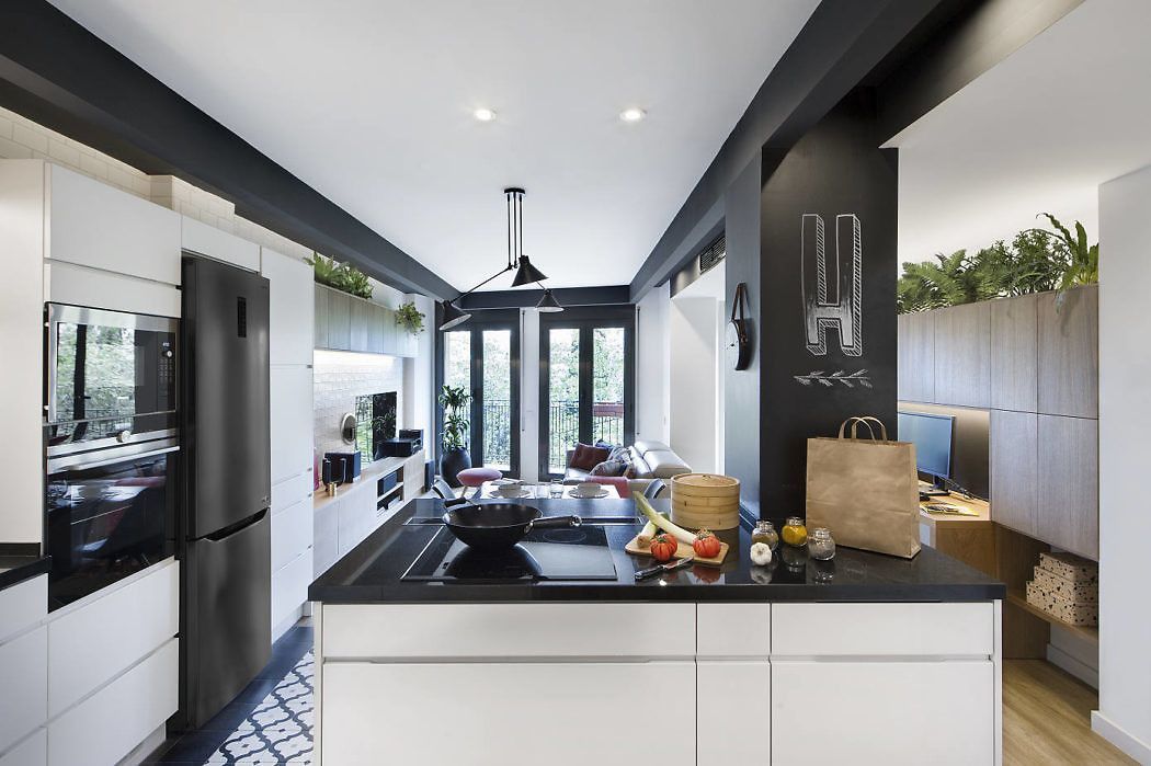 Szigetes konyha beépített főzőlappal és fekete hűtővel