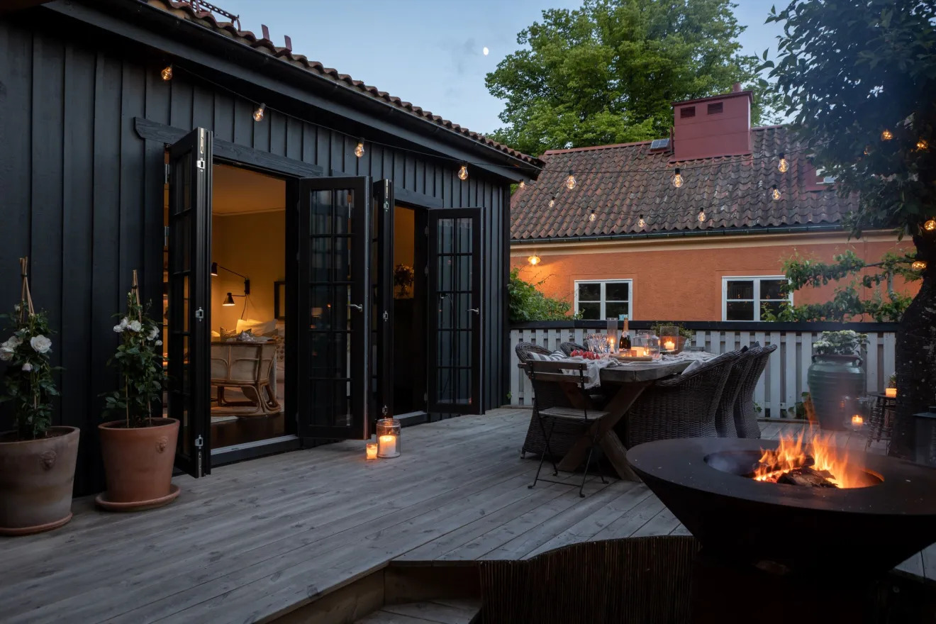 Feketére festett svéd faház terasszal és tűztállal