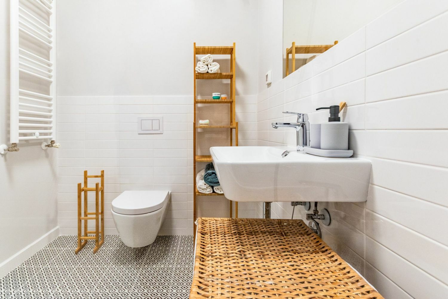Fehér fürdőszoba apró mintás padlólapokkal és fa kisbútorokkal, fonott tárolókkal