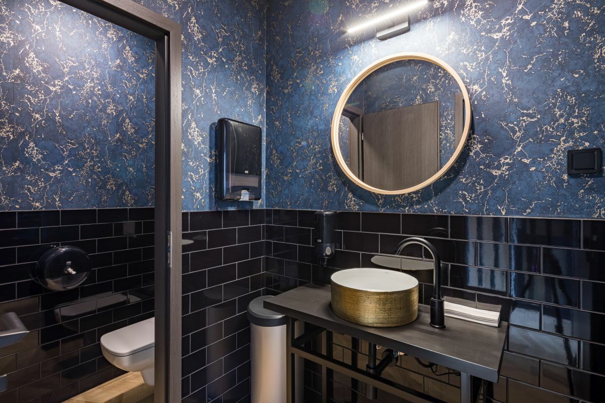 Elegáns arany színű mosdó és modern tükör a mellékhelyiségben